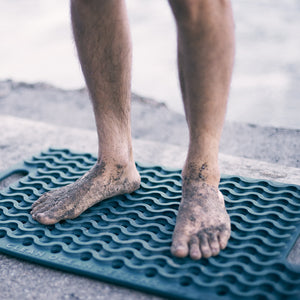 bare sandy feet standing on blue green ocean designs floor mat