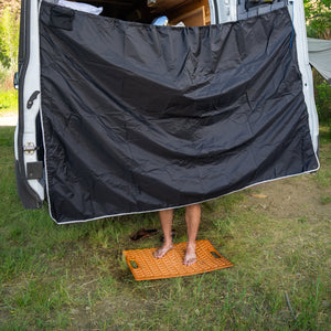 man showering behind curtain in back of camping van